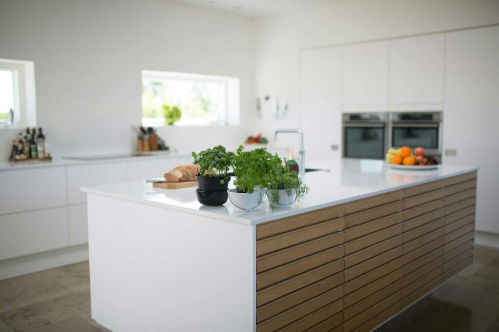 open kitchen with a white countertop island and wood paneling down the side of the island